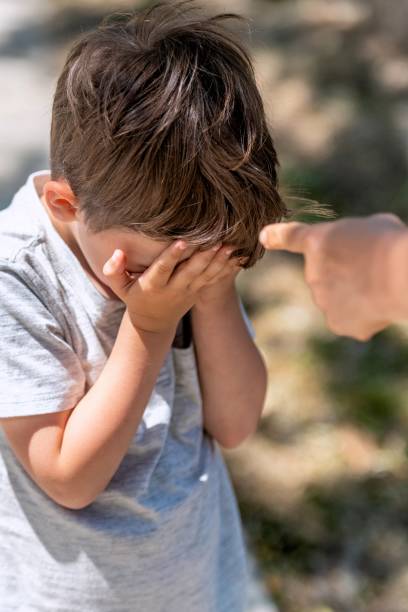 teachers index finger pointing to a crying boy that hides his face behind his hands - mother holding child pointing imagens e fotografias de stock