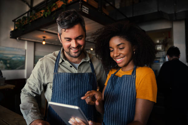 istock Waiter and waitress scrolling on tablet choosing menu options for customer in trendy cafe 1313336998