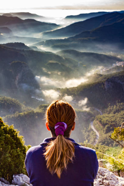 Woman observes a mountain landscape at sunrise in Montanejos, Valencia, Spain. stock photo