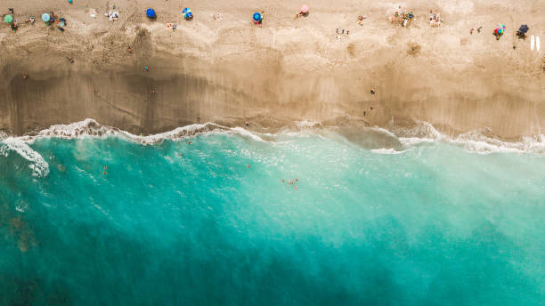 panoramica aerea diretta di una vibrante costa dell'oceano verde acqua e ombrelloni colorati su giove, in florida a metà giornata durante covid-19 nell'aprile del 2021 - gulf coast states foto e immagini stock