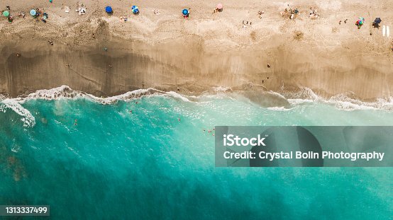 istock Direct Aerial Overview of a Vibrant Teal Ocean Seashore and Colorful Beach Umbrellas on Jupiter, Florida at Mid-Day During COVID-19 in April of 2021 1313337499