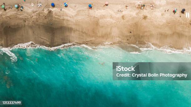 Direct Aerial Overview Of A Vibrant Teal Ocean Seashore And Colorful Beach Umbrellas On Jupiter Florida At Midday During Covid19 In April Of 2021 Stock Photo - Download Image Now