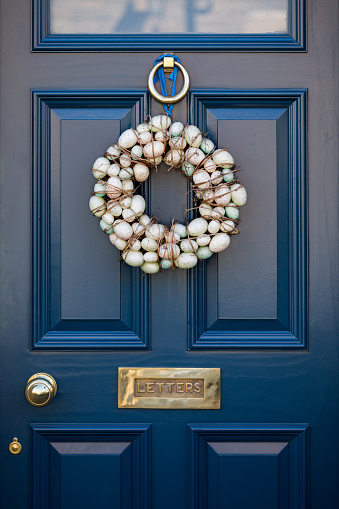 Easter egg wreath door decoration on a dark blue painted front door in an English village in Spring