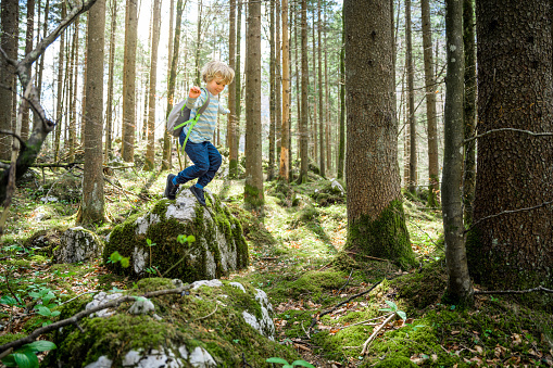 Little boy having a blast spending time in the nature. Jumping from rock to rock.