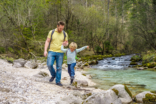 Mother and son enjoying a walk by the river. Walking around exploring nature while holding hands