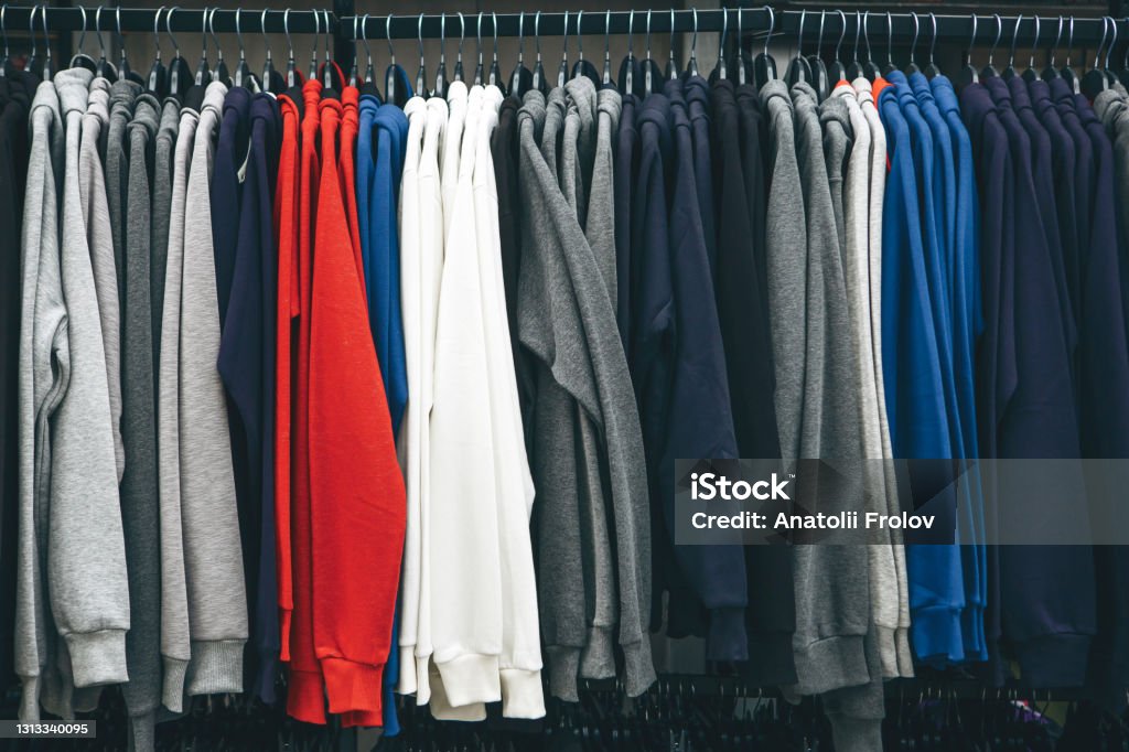 Many sweatshirts or pullovers hang on a hanger in a store Many sweatshirts or pullovers hang on a hanger in a store or closet. A varied wardrobe and a selection of clothes. Sweatshirt Stock Photo
