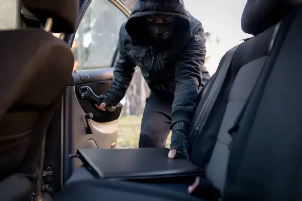 A thief trying to steal a car. Using various tools to open the door and steal stuff.