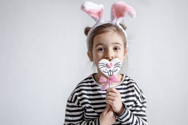 istock Little girl with decorative Easter bunny ears and Easter gingerbread on a stick. 1313348053