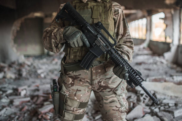 istock Armed female soldier in camouflage uniform with weapons in war zone 1313348259