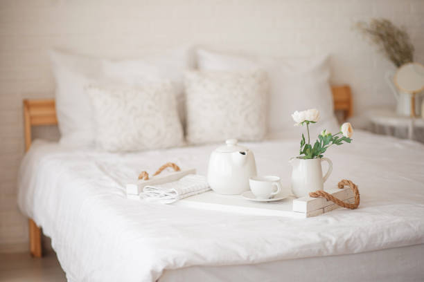 Cozy bedroom in light colors. Flowers, breakfast in bed. stock photo