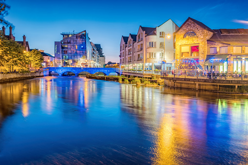 People enjoy the evening on the Garavogue River waterfront in downtown Sligo Ireland at night.