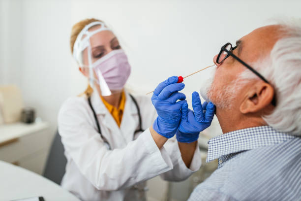 istock Doctor in protective workwear taking nose swab test from senior man 1313351446