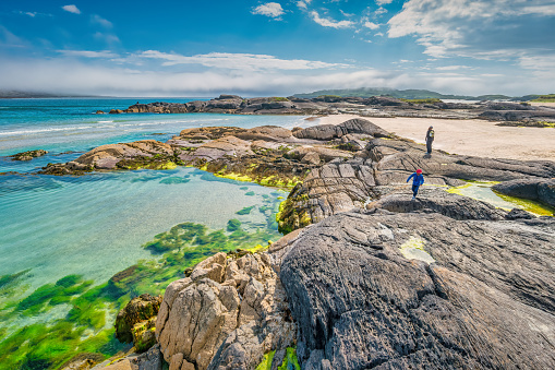 Mother and son enjoy the rocks of Derrynane beach on the Ring of Kerry, Ireland on a sunny day.