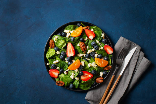istock Summer salad with berries, cheese and spinach on blue background 1313353203