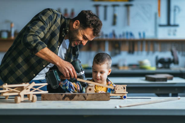 istock Boy and his father in carpenter workshop playing with wooden toy 1313355458