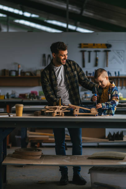 istock Dad showing son wooden toy that he made in workshop 1313355544
