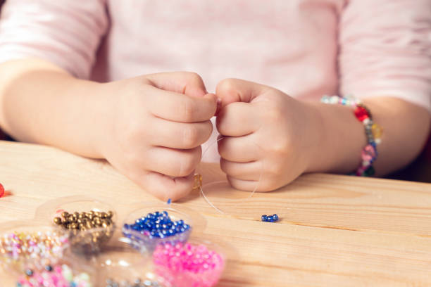 istock The child makes jewelry with his own hands, stringing colorful beads on a thread 1313356755