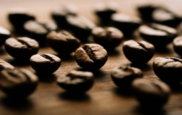 detalhe do grão de café na mesa de madeira marrom - coffee crop brown bean beige - fotografias e filmes do acervo