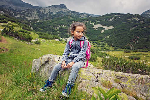 Little hiker girl is resting in a mountain
