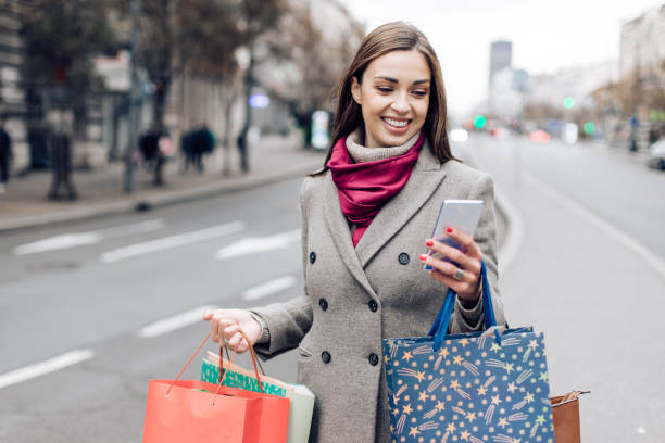 istock Young woman walking after shopping and using phone 1313362130