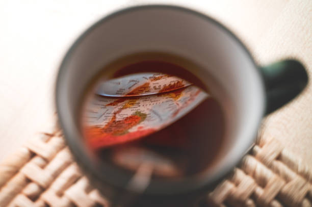 vue aérienne sur la tasse noire avec le sachet de thé et l’accent sélectif sur la réflexion du globe illuminé - illumunated photos et images de collection