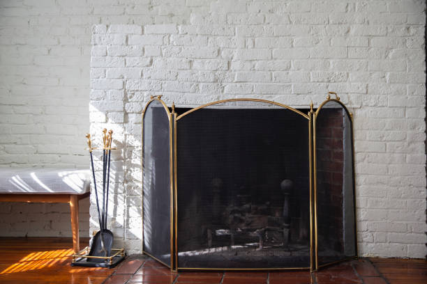 istock Fireplace with black fire guard screen and tools like shovel and poker. White brick wall 1313363687