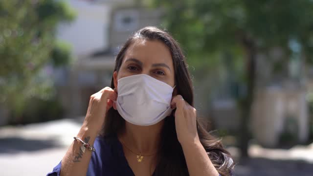 Portrait of a mid adult woman removing protective face mask outdoors