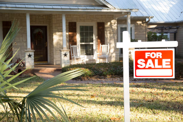 Home for sale with real estate sign. Front Yard. Home for sale with red and white real estate sign during the fall season. Fall season with leaves on ground. Front porch and windows in background. Residential neighborhood. Moving house, relocation concept. house for sale sign stock pictures, royalty-free photos & images