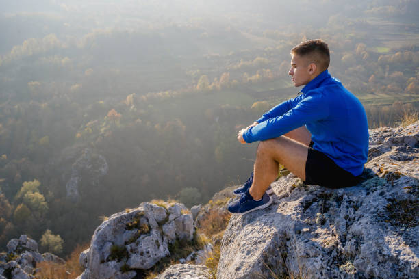 istock Man sitting at the top of mountain and looking at view 1313372221