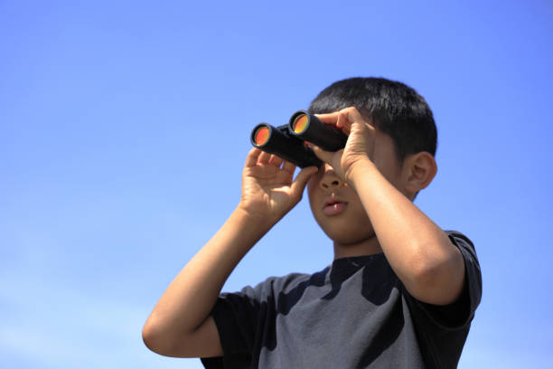 kid with telescope watching outdoor near window