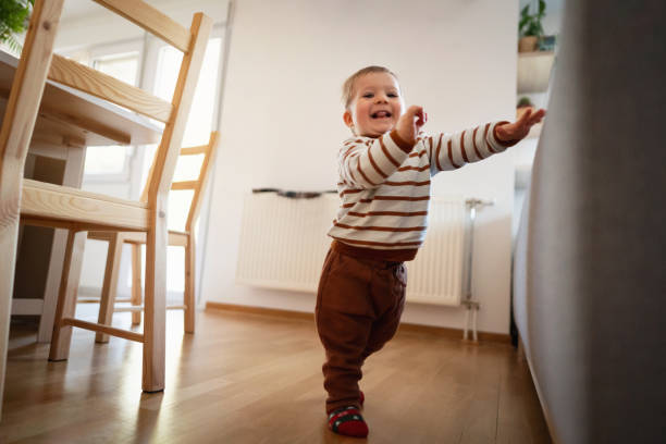 istock Happy baby boy making his first steps while holding on the sofa 1313379423
