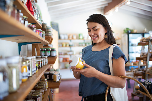 Mujer joven sonriendo comprando alimentos sanos y artesanales en pequeña tienda local photo