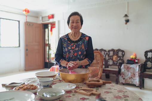Asian grandmother prepares traditional rice cakes by hand