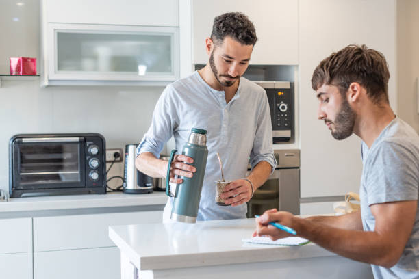 istock Young man writing in a paper while his boyfriend is preparing mate infusion 1313392334