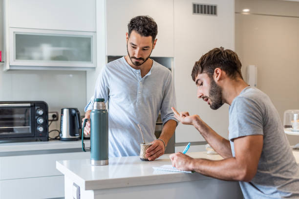 istock Young man writing in a paper while his boyfriend is preparing mate infusion 1313392336