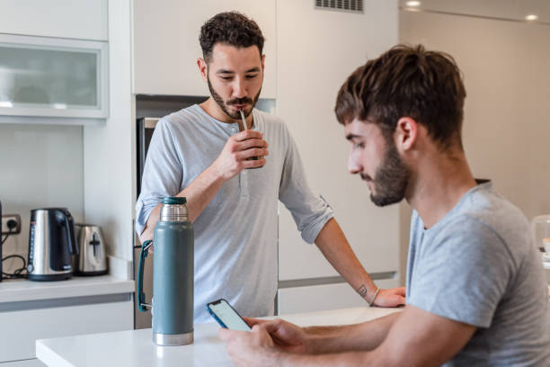 istock Young man using his smartphone while his boyfriend is preparing mate infusion 1313394187