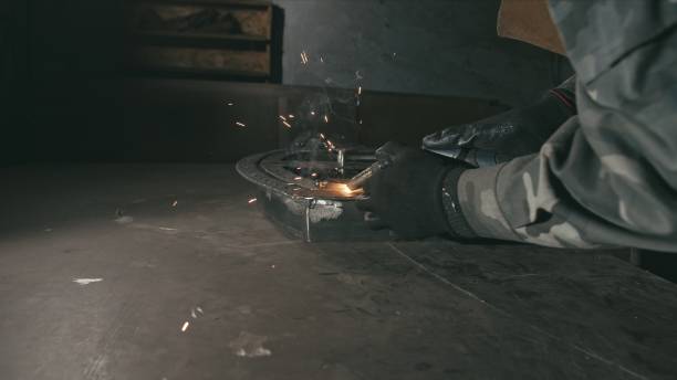 istock Forge workshop. Smithy. Worker in a welding hood helmet welds a part by electric welding. Sparks are reflected in the protective screen. 1313398984
