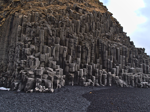 View of basaltic rock formations on famous beach Reynisfjara with black pebble stones on the southern coast of Iceland in winter.