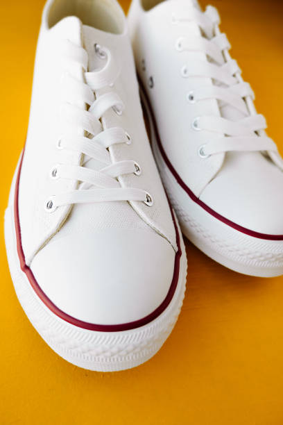 istock white new clean sneakers with white laces on a rubber sole on a bright yellow background. selective focus 1313408064
