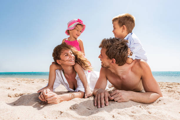 istock Young happy family talking while relaxing in sand on the beach. 1313410670