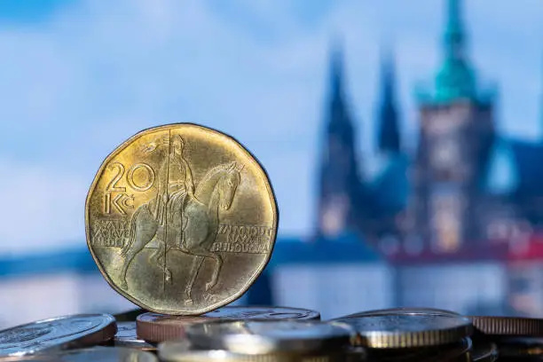 A 20 CZK coin and other coins against the background of out-of-focus fragments of Prague buildings