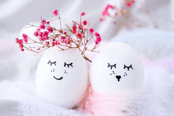 istock Minimal easter concept. Easter eggs with painted smiley faces and bird feather on pastel background. Wedding couple eggs. Married. Valentines day 1313413782
