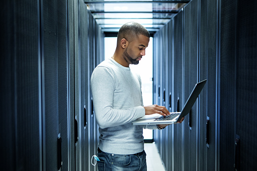 A black ethnicity male server technician working back at the office and server room after lockdown