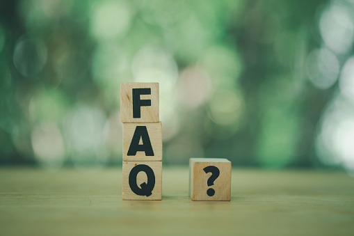 Close-up shot of FAQ and question marks wooden blocks. Wood letters as FAQ abbreviation