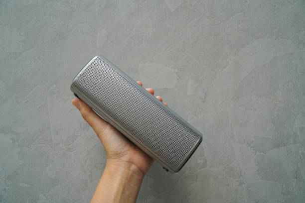 istock close up people hold Bluetooth speaker in hand for music connection with loft wall background 1313417944