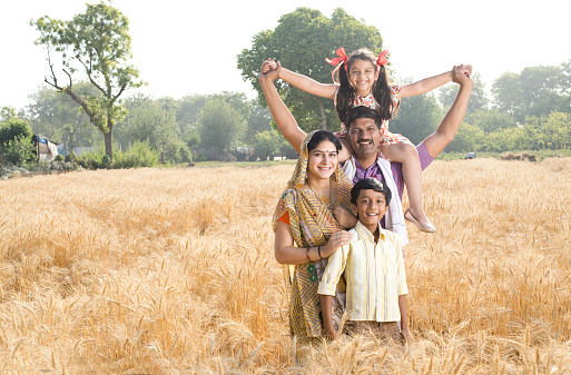 Happy parents with children having fun on agricultural field