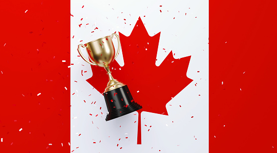 Colorful confetti falling onto a gold cup sitting over Canadian flag background. Horizontal composition with copy space. Front view. Championship concept.