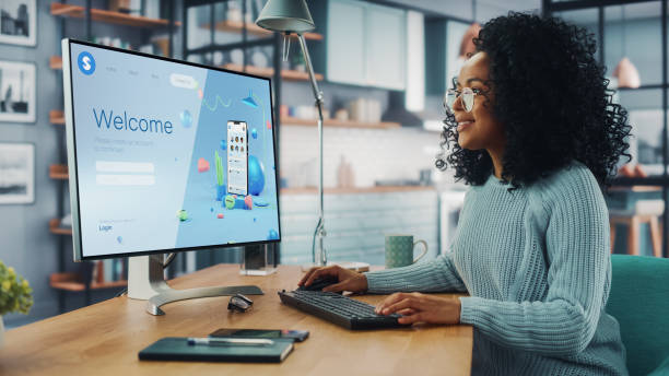 istock Handsome Black Female is Using Desktop Computer that Shows Welcome Page of a Popular Social Network. Freelance Woman Working Over the Internet as a Social Network Marketer. 1313422698