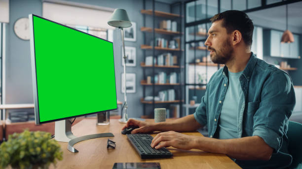istock Handsome Caucasian Specialist Working on Desktop Computer with Green Screen Mock Up Display at Home Living Room. Freelance Man Chatting to Clients Over the Internet on Social Networks. 1313422731