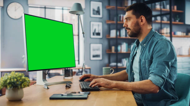 istock Handsome Caucasian Specialist Working on Desktop Computer with Green Screen Mock Up Display at Home Living Room. Freelance Man Chatting to Clients Over the Internet on Social Networks. 1313422784